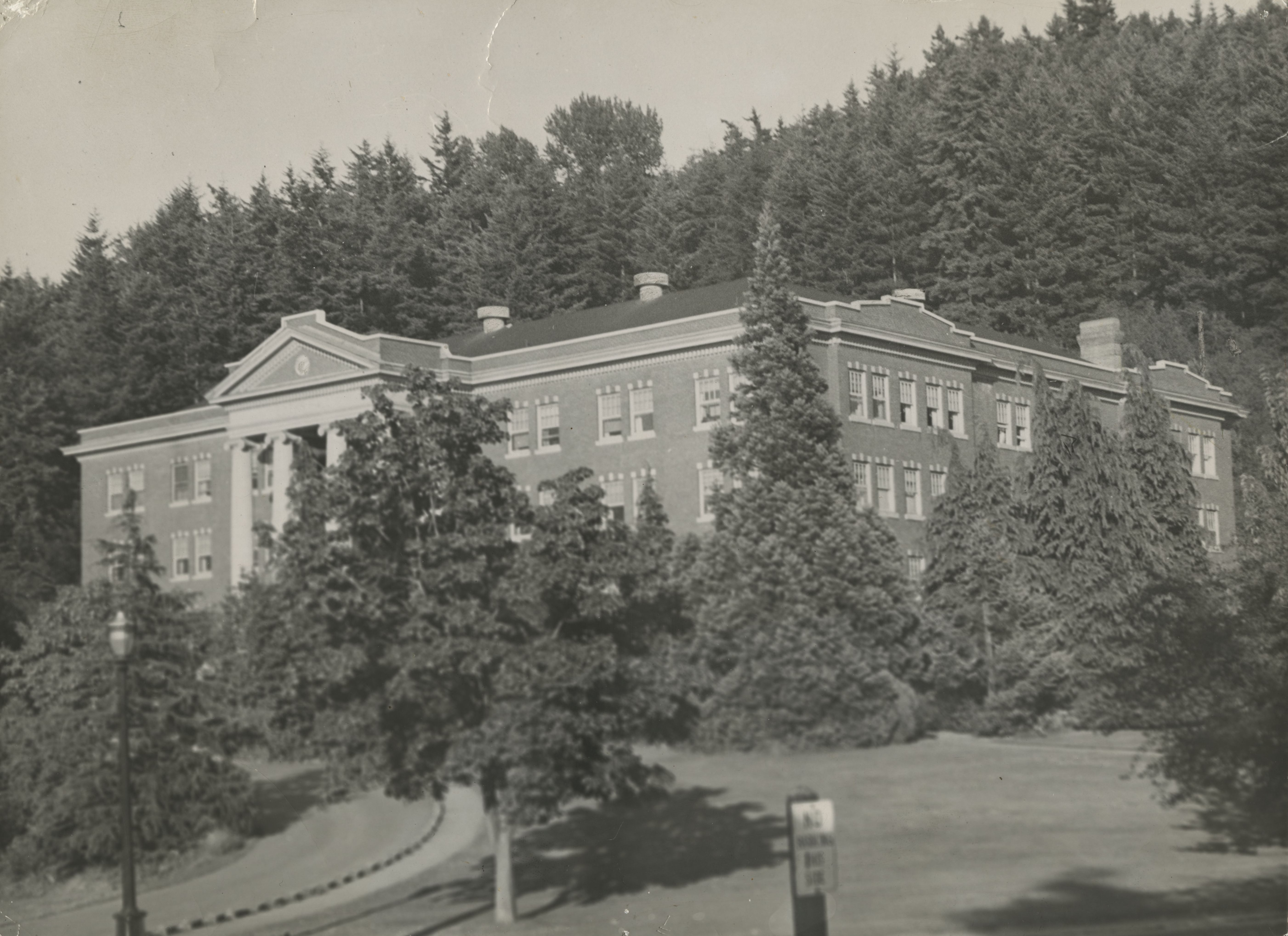 1945 photo of Edens Hall, with the top of the redwood tree jutting up over the top of the building&#039;s roof