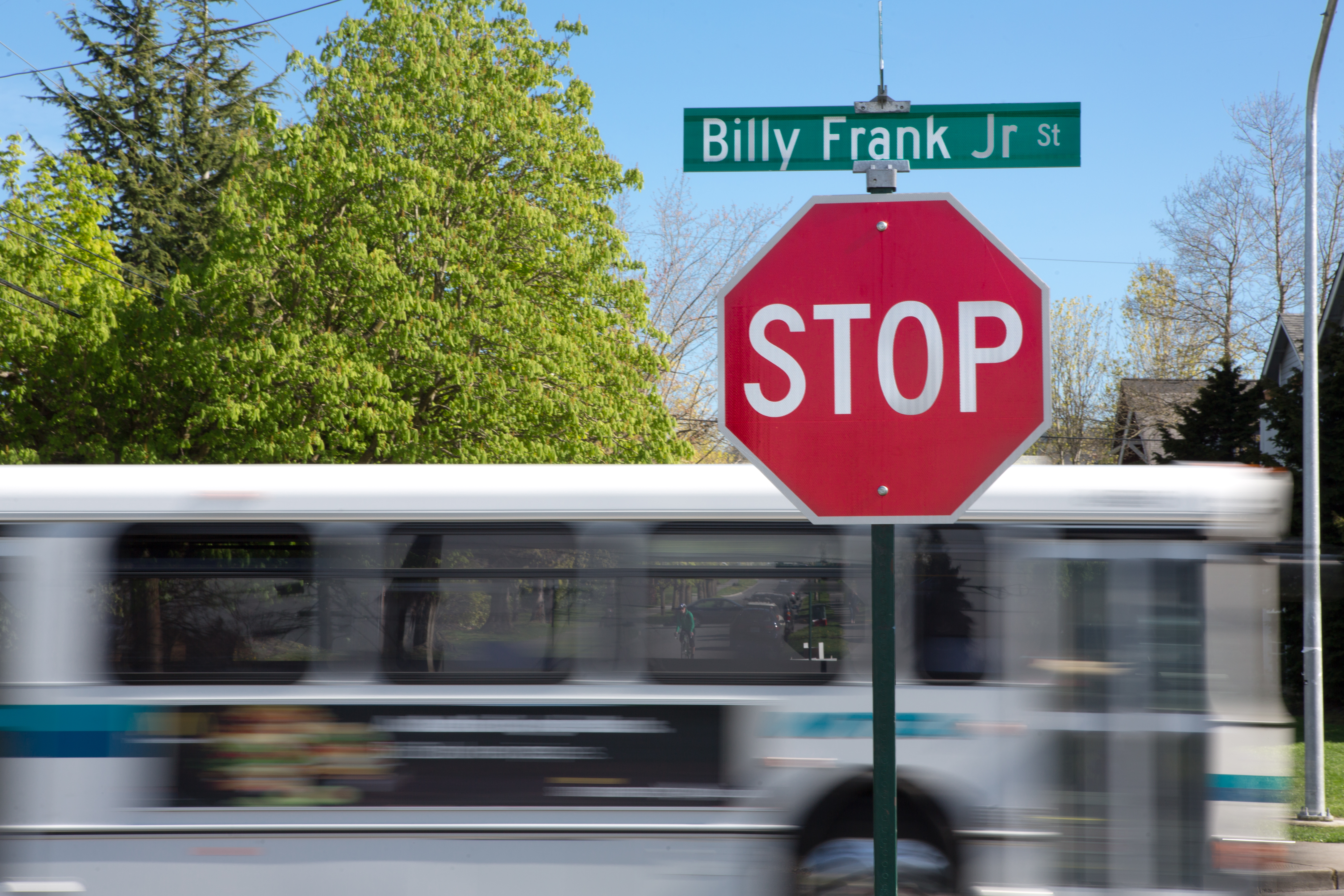 A bus passes a stop sign with a street sign atop: Billy Frank Jr. St.