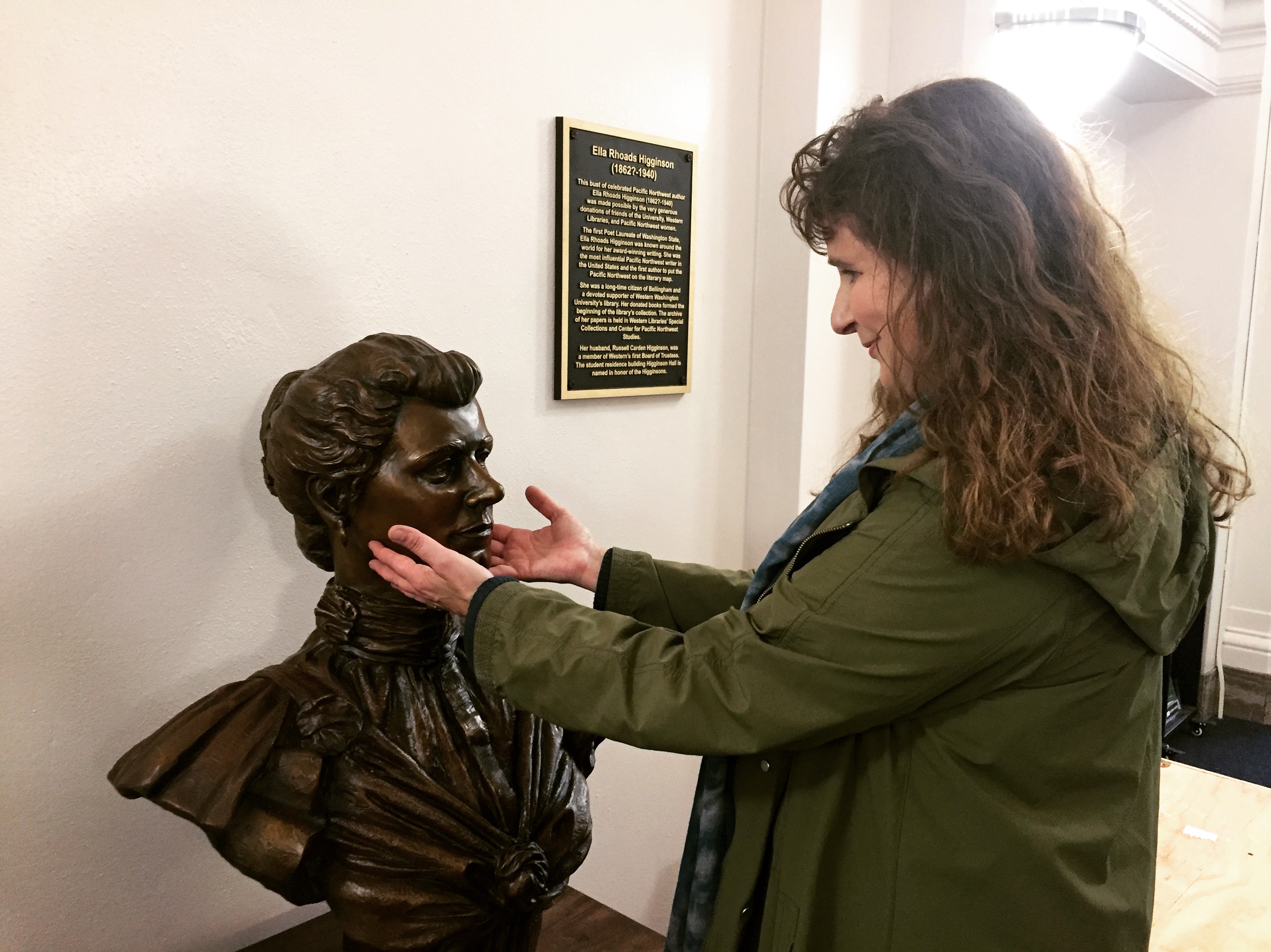 A woman touches the face of a bronze bust