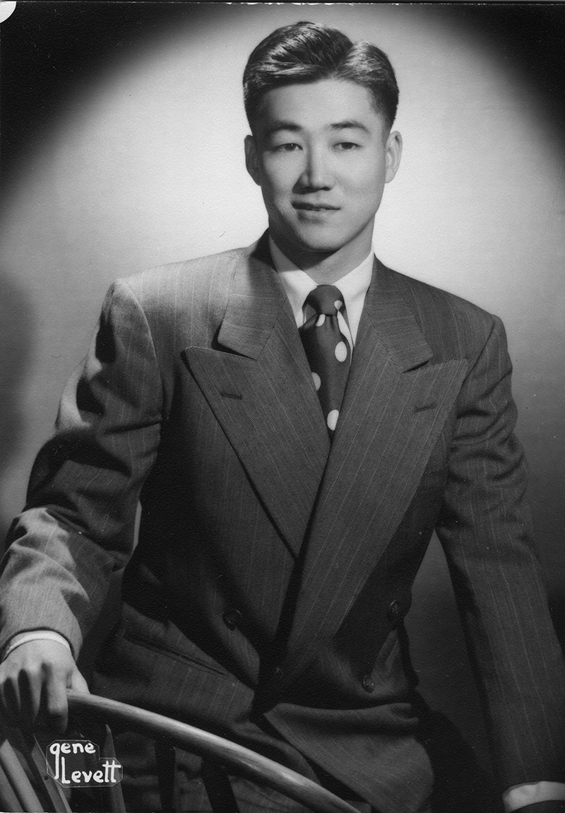 black and white portrait of a young man wearing a 1950s-style striped suit with polka-dot tie