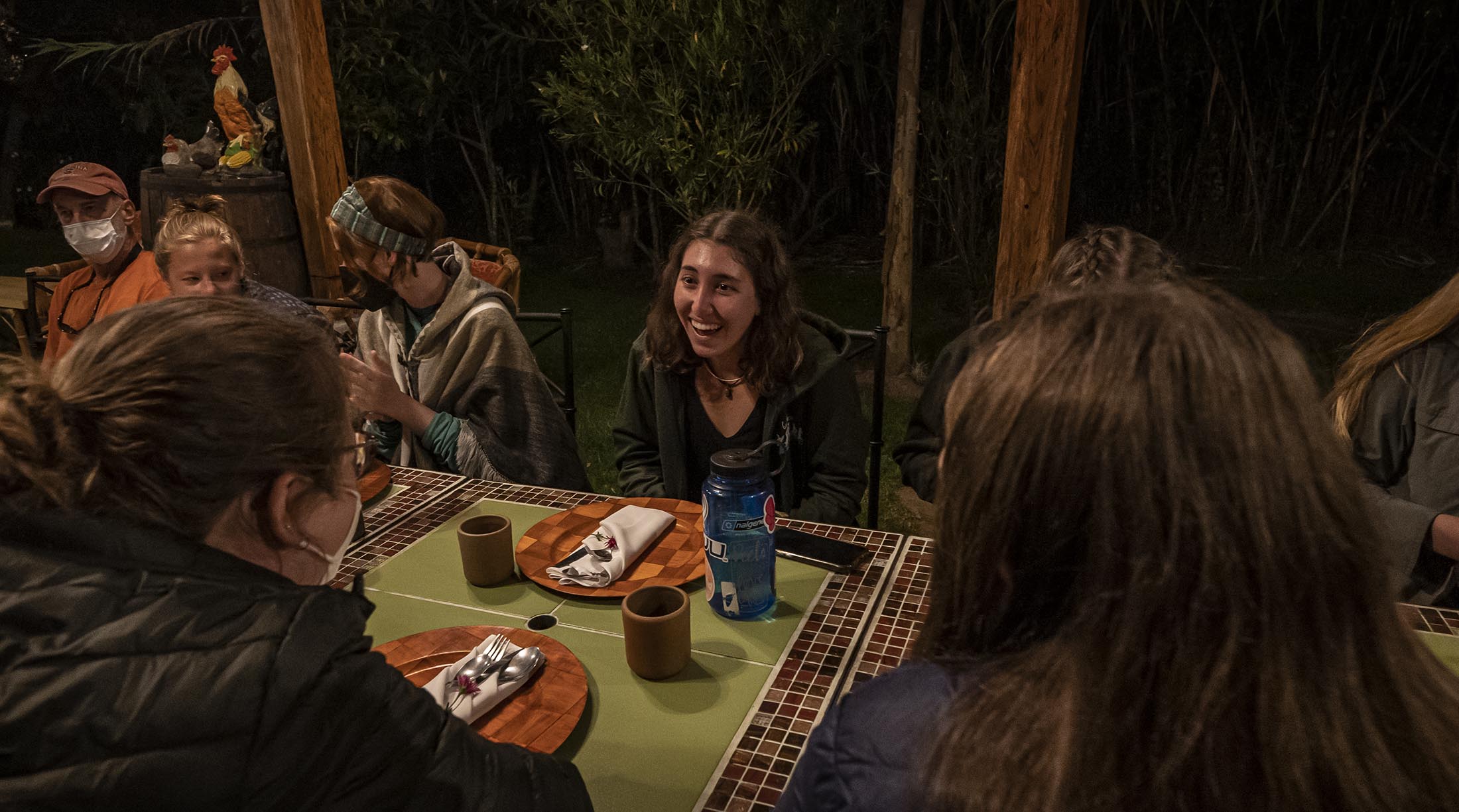 A closeup of a student at dinner, smiling enthusiastically as she talks with peers