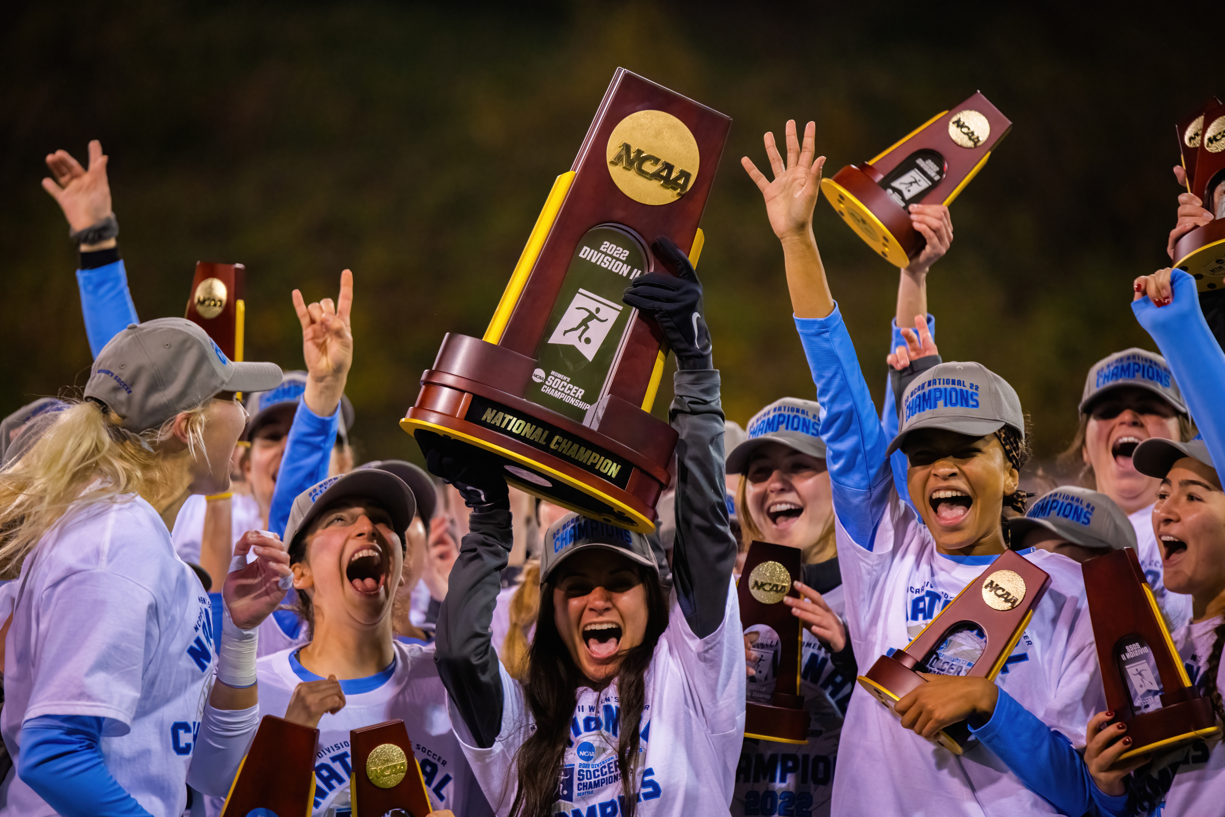 Western women's soccer team cheers and hoists their trophies after winning the NCAA II national championships