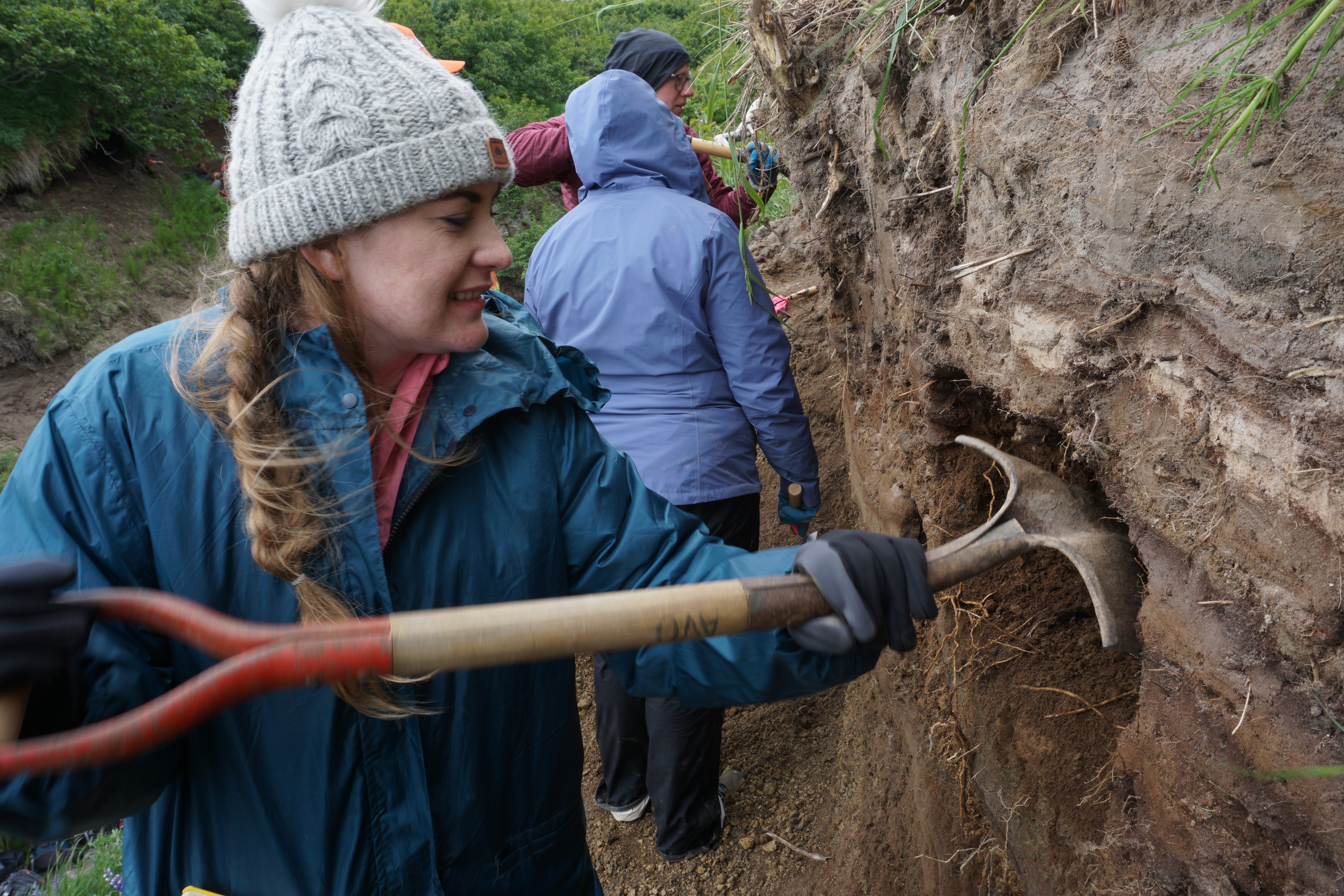 Sloane Kennedy uses a shovel to scrape dirt from an embankment.