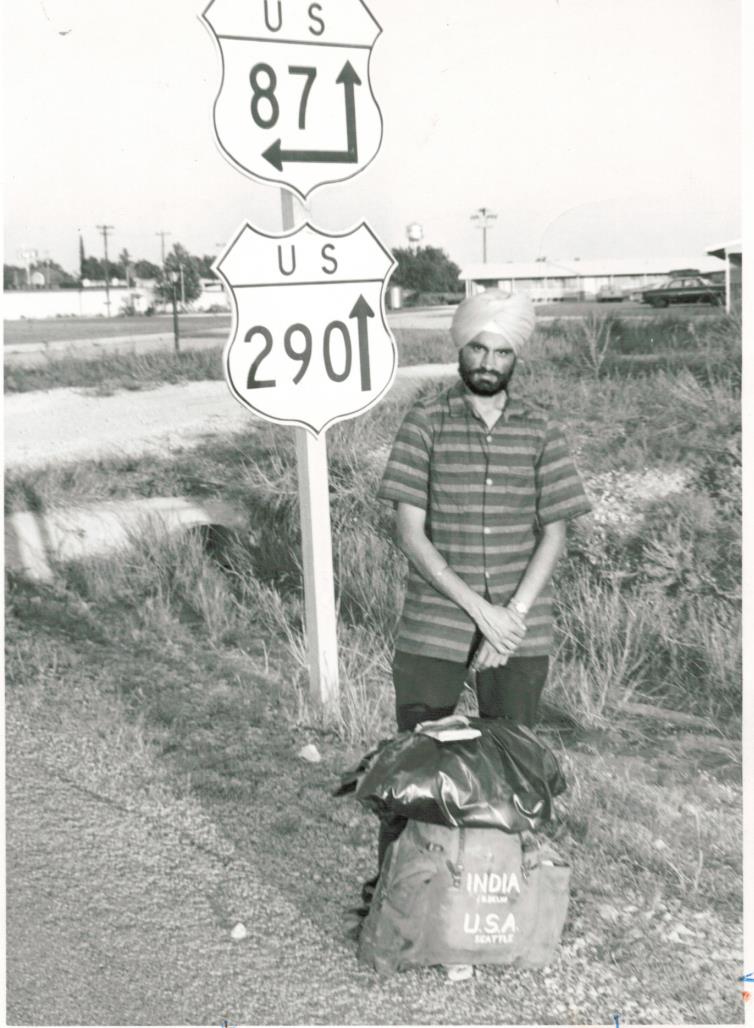 Hardev Singh Shergill stands by an interstate sign, his backpack at his feet.