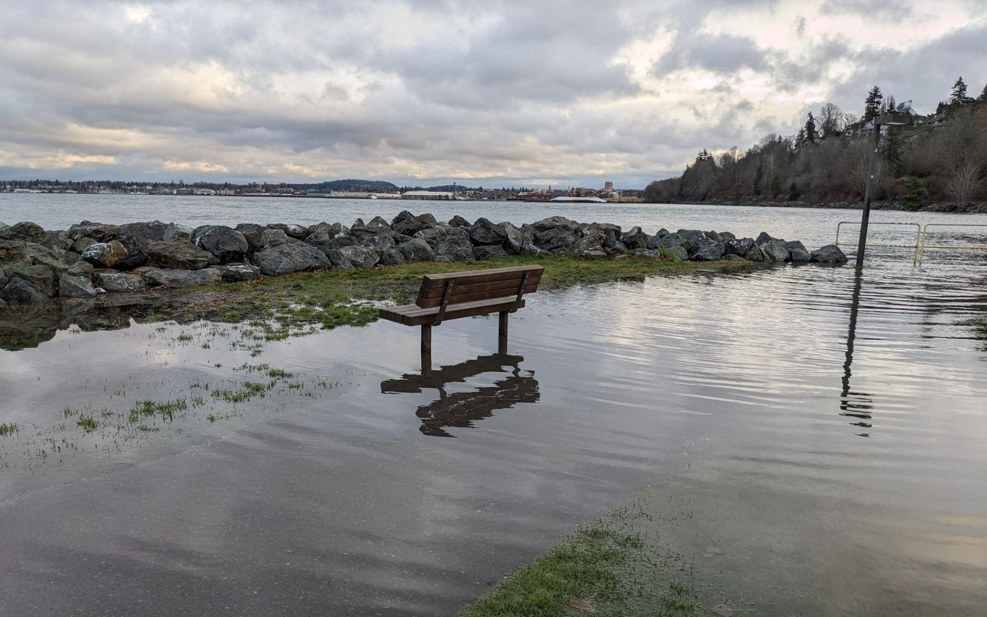 A bench in Boulevard Park, normally on the shore, is surrounded by water.