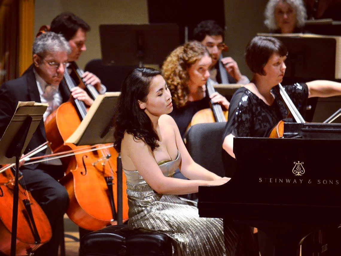 Pianist Di Wu performs with an orchestra behind her. 