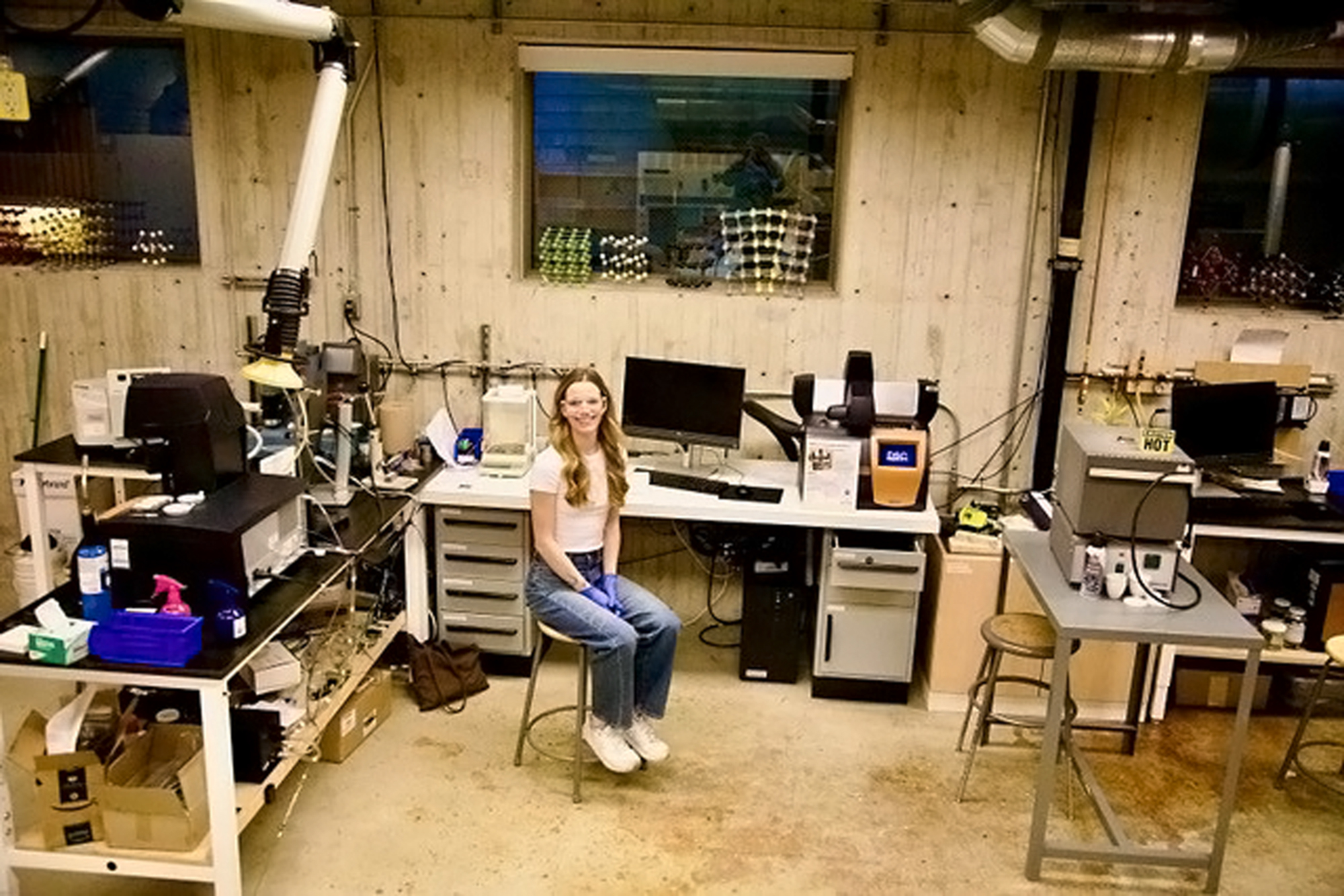 A student sits in the middle of a scientific laboratory, surrounded by equipment