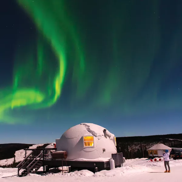 green auroral lights glimmer over a dome-shaped structure 