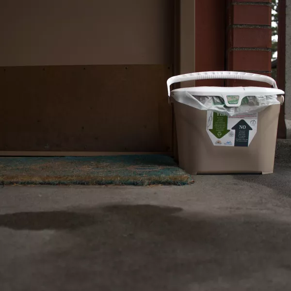 a portable compost bin sits outside a dorm room