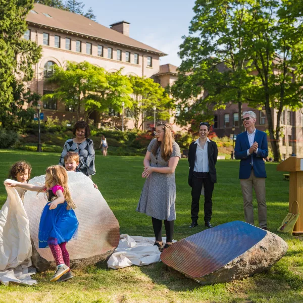 AS Child Development Center kids  Nox Tuigamala, Ivie Gilbert, and Calder Amos remove the coverings from  “Split Stone (Northwest)” during the  sculpture’s unveiling ceremony in May. Watching are several adults including artist Sarah Sze.
