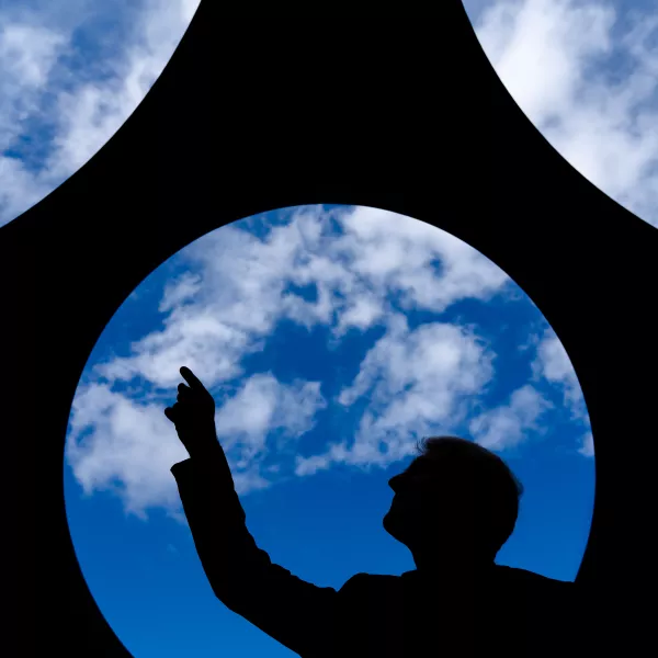A man can be seen in profile against Skyviewing Sculpture an the sky. 