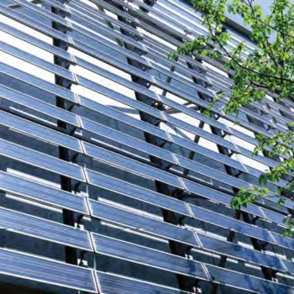 rows of solar panels line the outside of a building, next to a leafy green tree