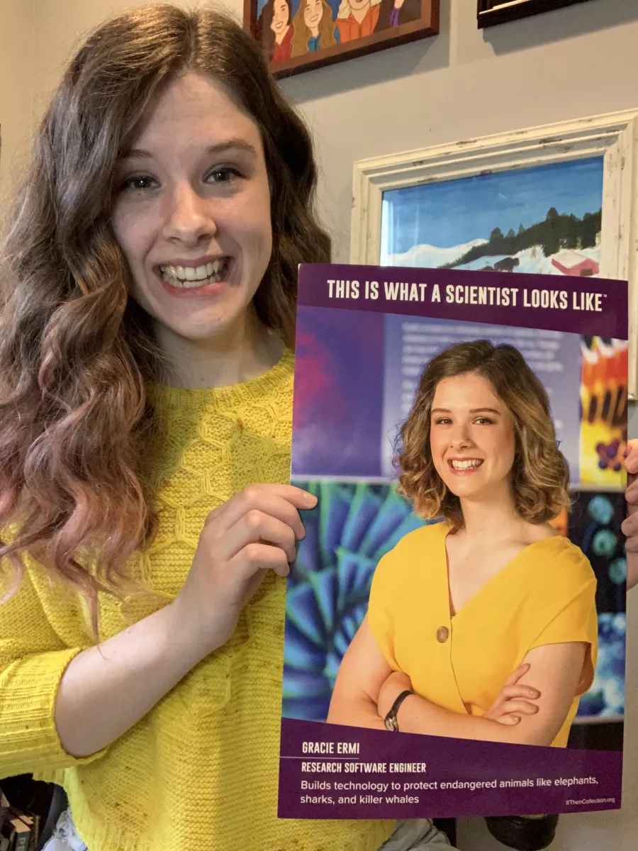 Gracie Ermi holds a poster of herself with the words This is what a scientist looks like.