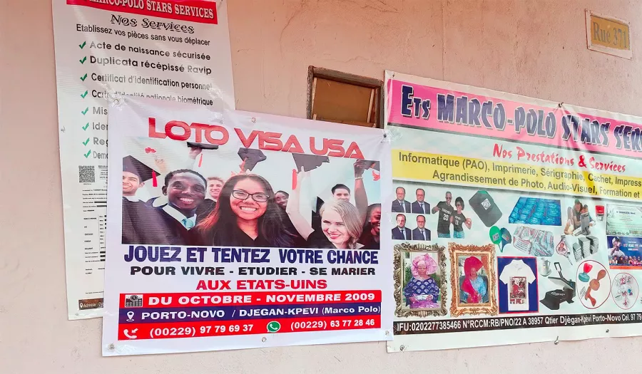 Several Posters plastered to a wall, all in French, including one that says Loto Visa USA, Jouez et tentez votre chance , with a photo of happy graduates wearing regalia. 