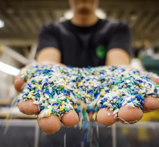 a pile of multi-colored plastic pieces run through a person&#039;s hands