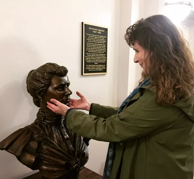 A woman touches the face of a bronze bust