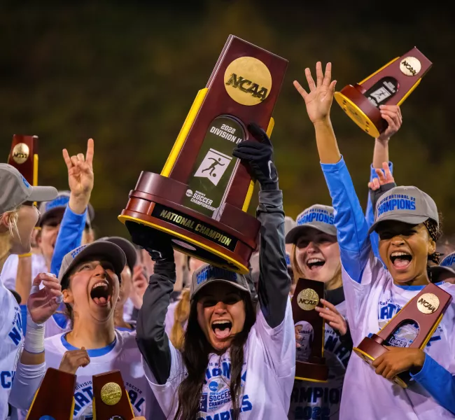 Western women's soccer team cheers and hoists their trophies after winning the NCAA II national championships